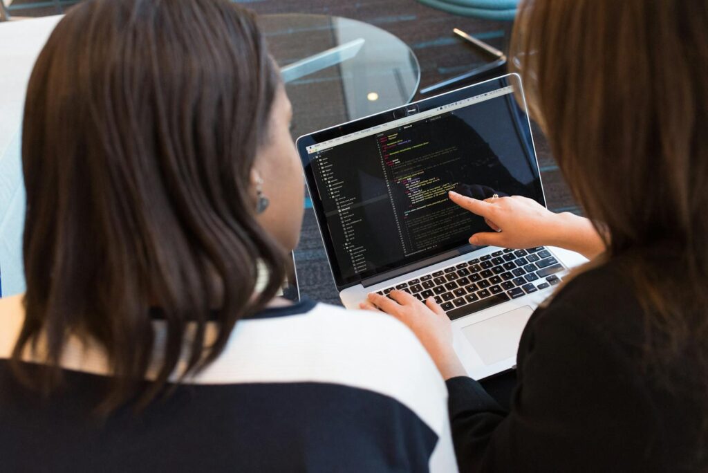 Mastering Ecommerce Website Development: A Practical Guide for Success 9 Two women working together on software programming indoors, focusing on code.