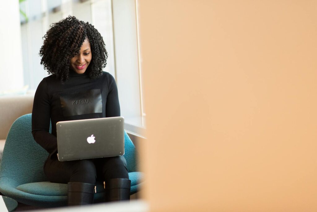 Best Email Hosting for Small Business Success in 2025 10 African American woman happily working on a laptop in a modern office setting.