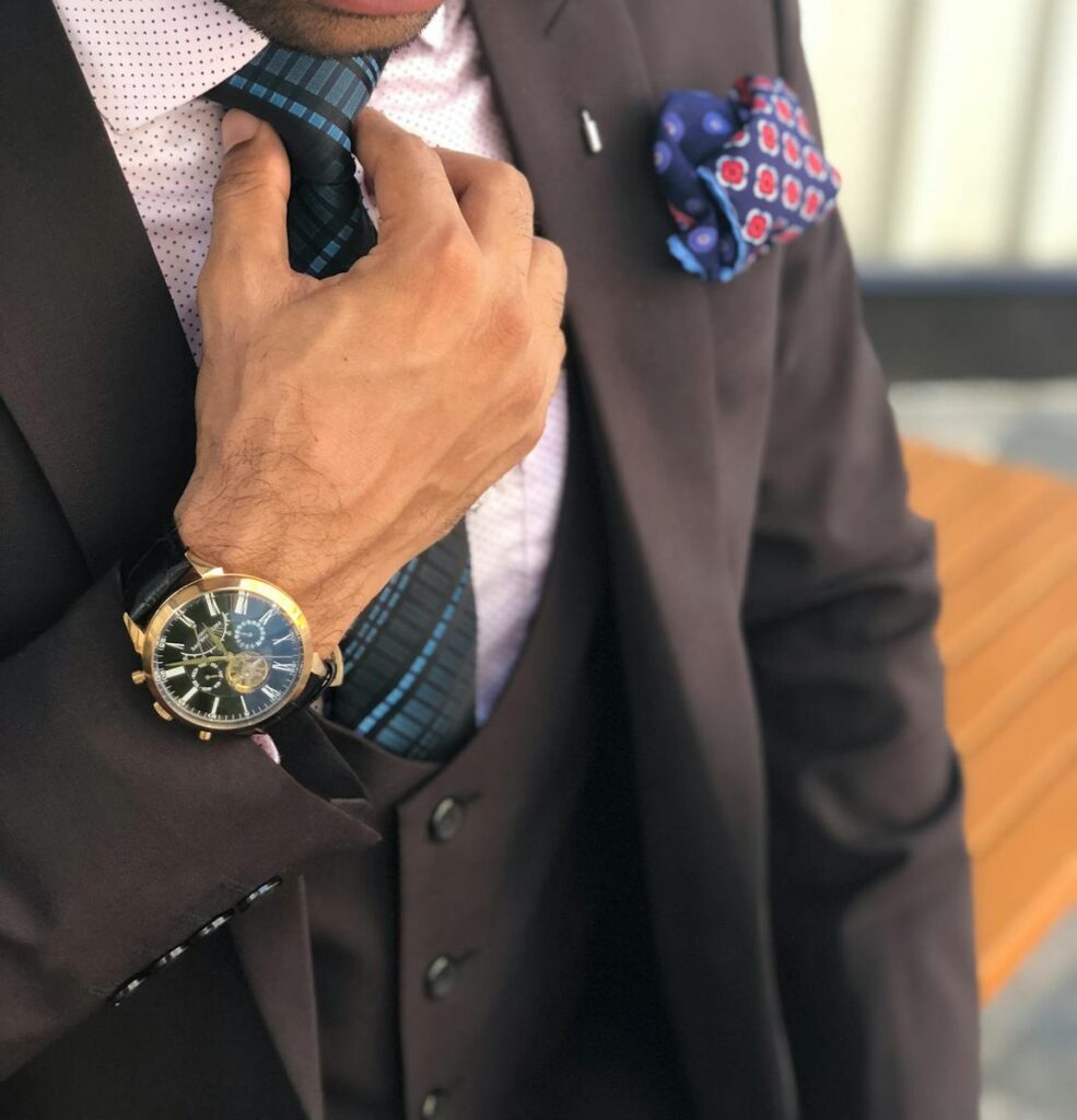 The Essential Guide to Choosing the Right Small Business Consultant 5 Elegant close-up of a man in a designer suit adjusting his tie, showcasing luxury fashion.