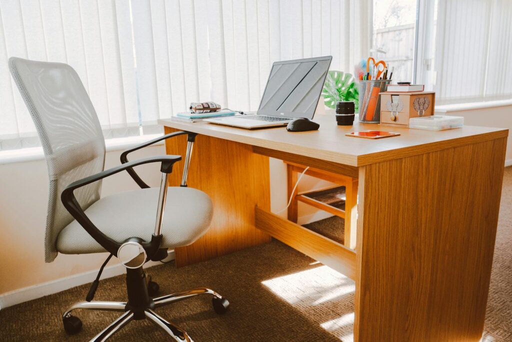 The Essential Guide to Choosing the Right Small Business Consultant 7 A modern office workspace featuring a wooden desk, chair, laptop, and bright natural light.
