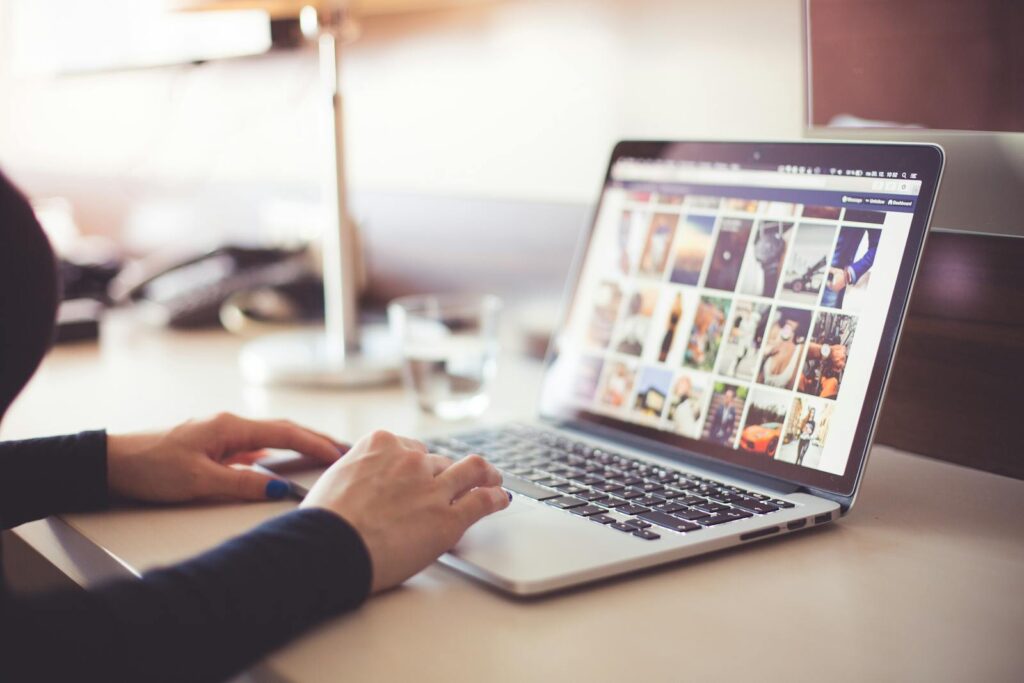 The Essential Guide to Choosing the Right Small Business Consultant 8 Close-up of hands typing on a laptop with an image gallery open on the screen.
