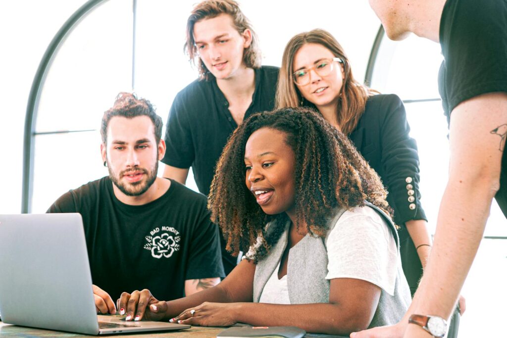 25 Unique Marketing Ideas for Small Business to Boost Growth 5 A diverse group of young professionals collaborating around a laptop in a modern office setting. Perfect for business or tech concepts.