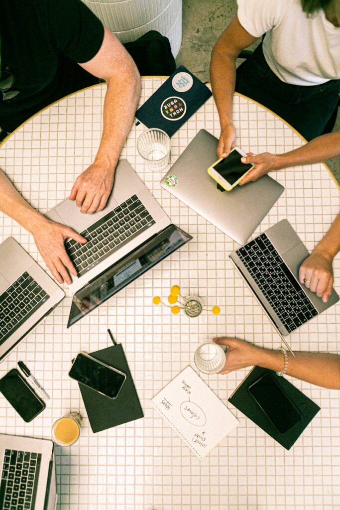 25 Unique Marketing Ideas for Small Business to Boost Growth 2 Top view of a team collaborating with laptops, phones, and notes in a modern office.