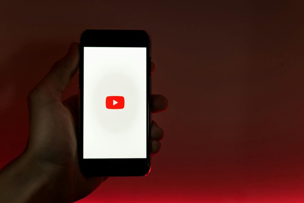 Is YouTube Considered Social Media? 9 A hand holding a smartphone displaying the YouTube app against a red background.