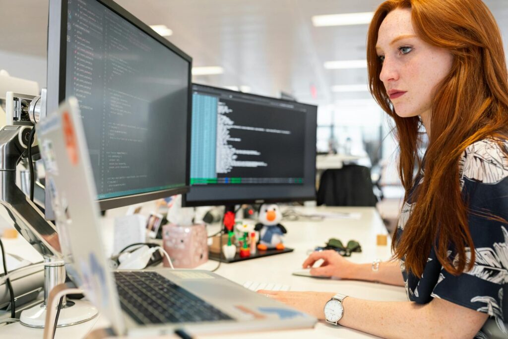 Mastering Ecommerce Website Development: A Practical Guide for Success 10 A focused female software engineer coding on dual monitors in a modern office.