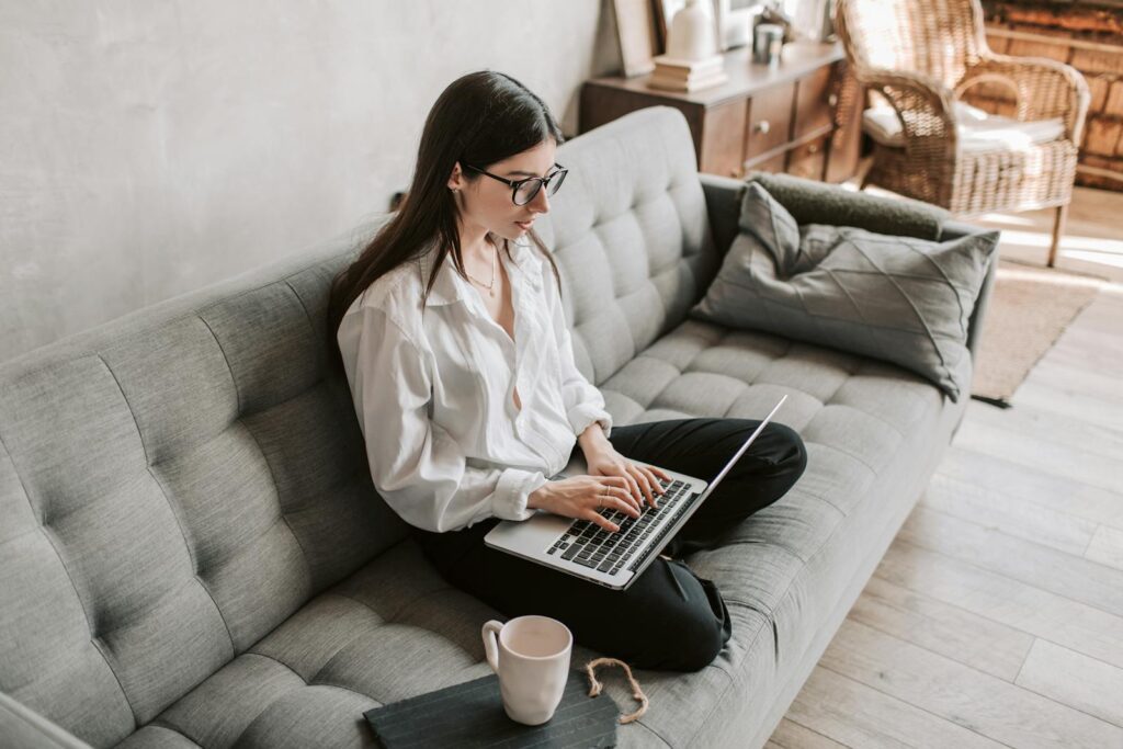 Best Email Hosting for Small Business Success in 2025 11 Woman in a cozy home setting working on a laptop for remote work and relaxation.