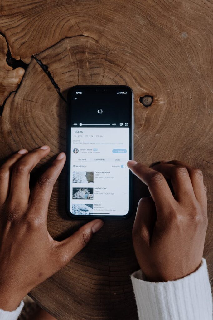 Is YouTube Considered Social Media? 11 Overhead view of hands browsing videos on a smartphone placed on a wooden background.