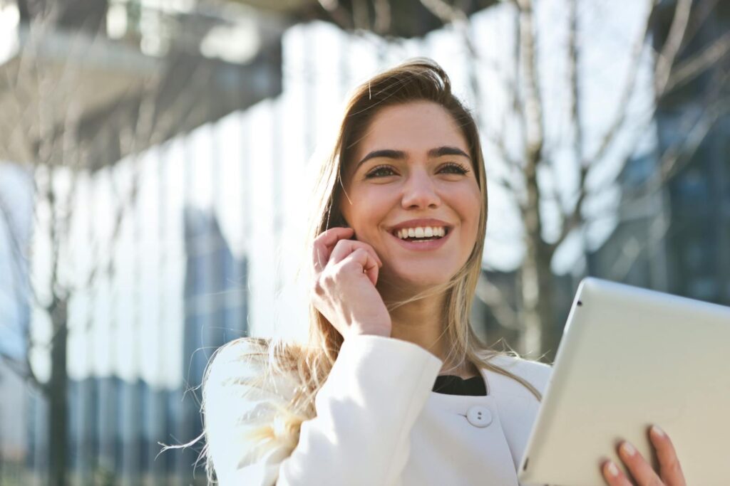 The Essential Guide to Choosing the Right Small Business Consultant 2 Confident businesswoman using her tablet and phone, smiling outdoors in sunlight.