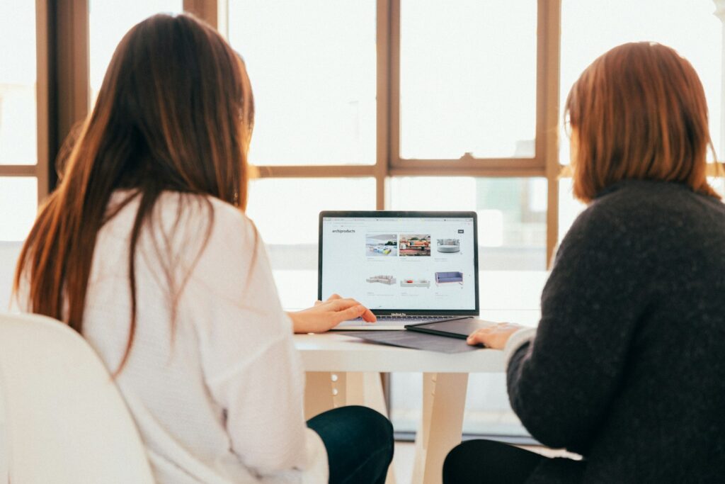 43 Creative Website Ideas to Inspire Your Next Project in 2025 4 two women talking while looking at laptop computer