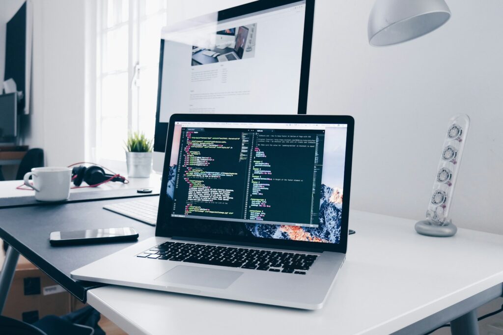 How to Code a Website: A Step-by-Step Guide for Beginners 3 A MacBook with lines of code on its screen on a busy desk