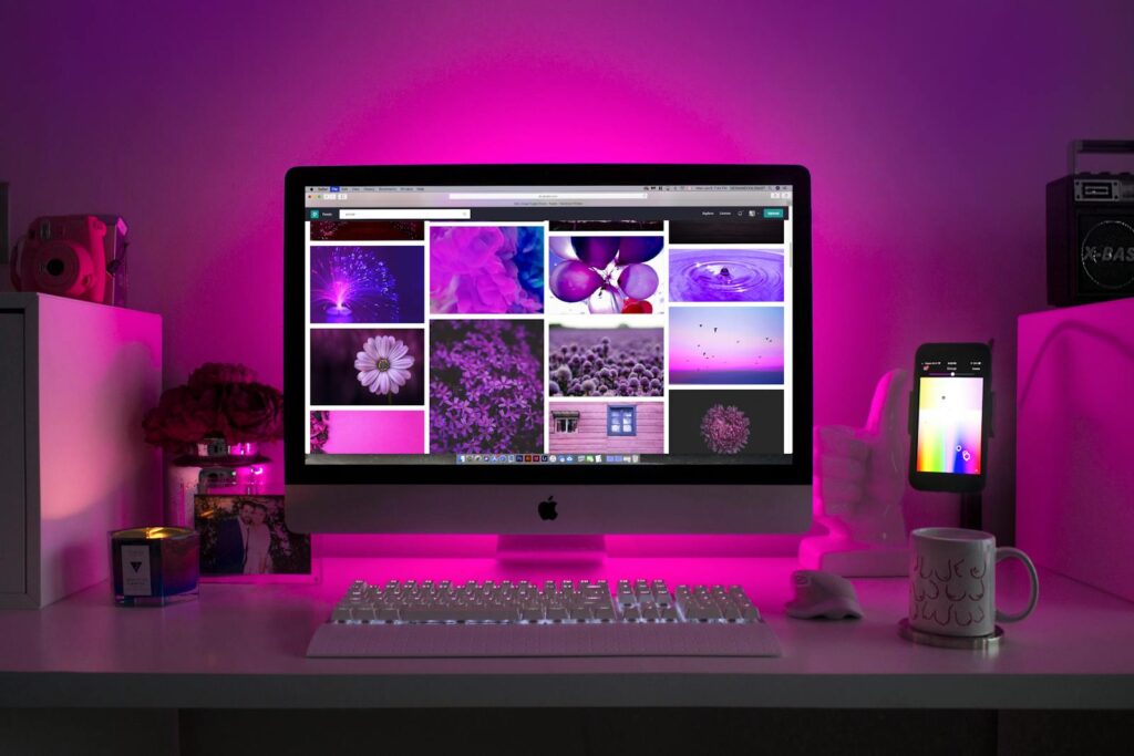 Custom Web Development at Priceless Consulting 7 Modern desk setup with neon lighting and a desktop computer displaying colorful images.