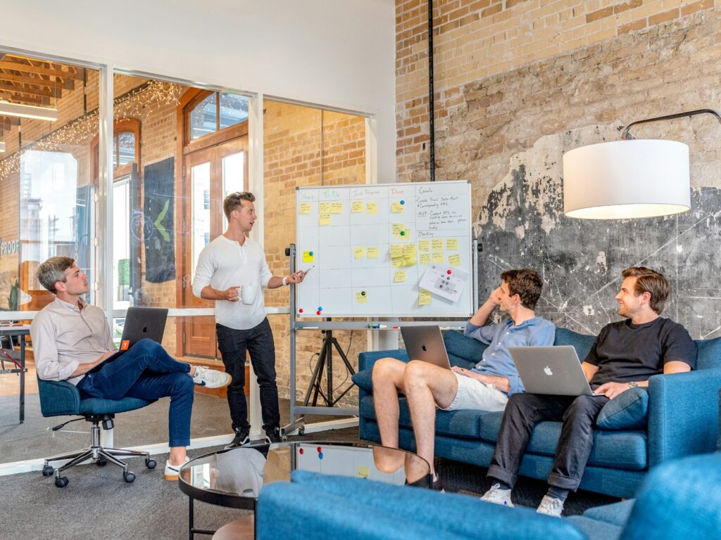 Digital Marketing Services for Small Business | Use Priceless Consulting As Your Marketing Strategy 4 three men sitting while using laptops and watching man beside whiteboard