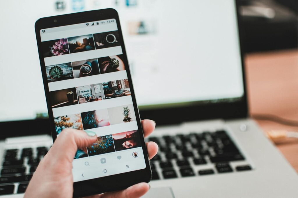 Decoding Social Media Marketing Packages: Your Complete Guide 5 A person uses a smartphone to browse social media in front of a laptop, emphasizing modern technology and lifestyle.