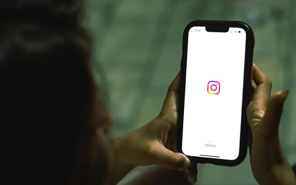 The Complete Social Media Audit Guide for Small Businesses 10 Close-up of a woman holding a smartphone displaying the Instagram app indoors.