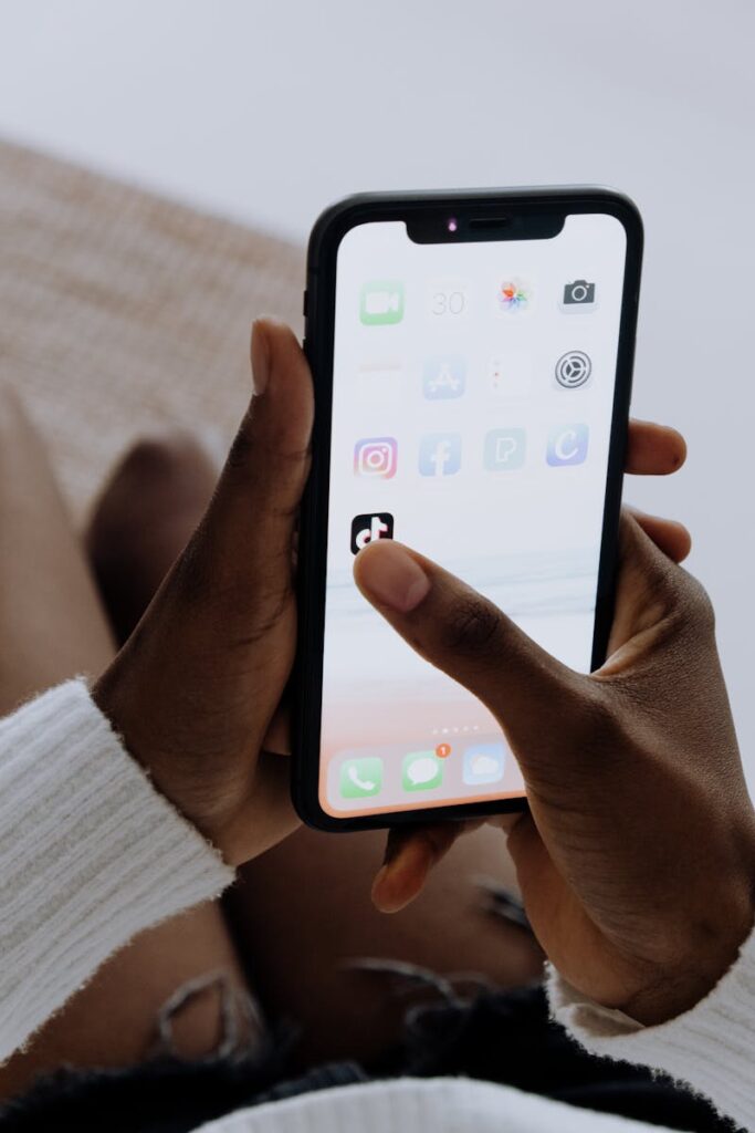 Social Media Consultant: Your Complete Guide to Success 11 Hands holding a smartphone showing various apps including TikTok in a close-up view.