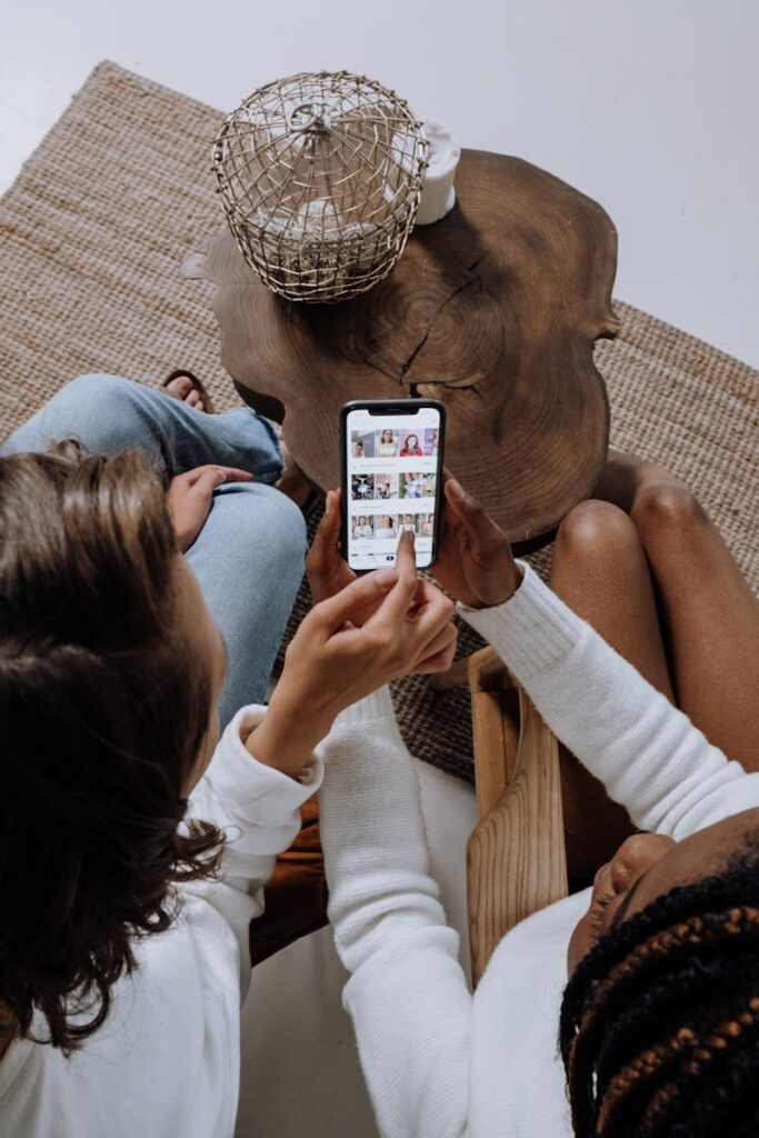 Social Media Consultant: Your Complete Guide to Success 9 Two people looking at social media on a smartphone at a wooden table.