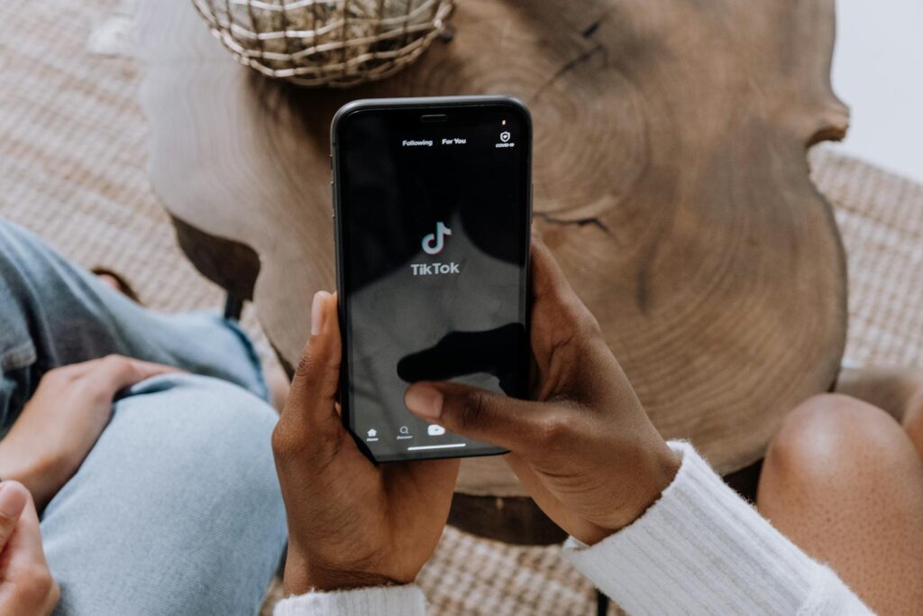 The Complete Social Media Audit Guide for Small Businesses 4 Close-up of hands holding a smartphone displaying the TikTok app interface on a wooden surface.