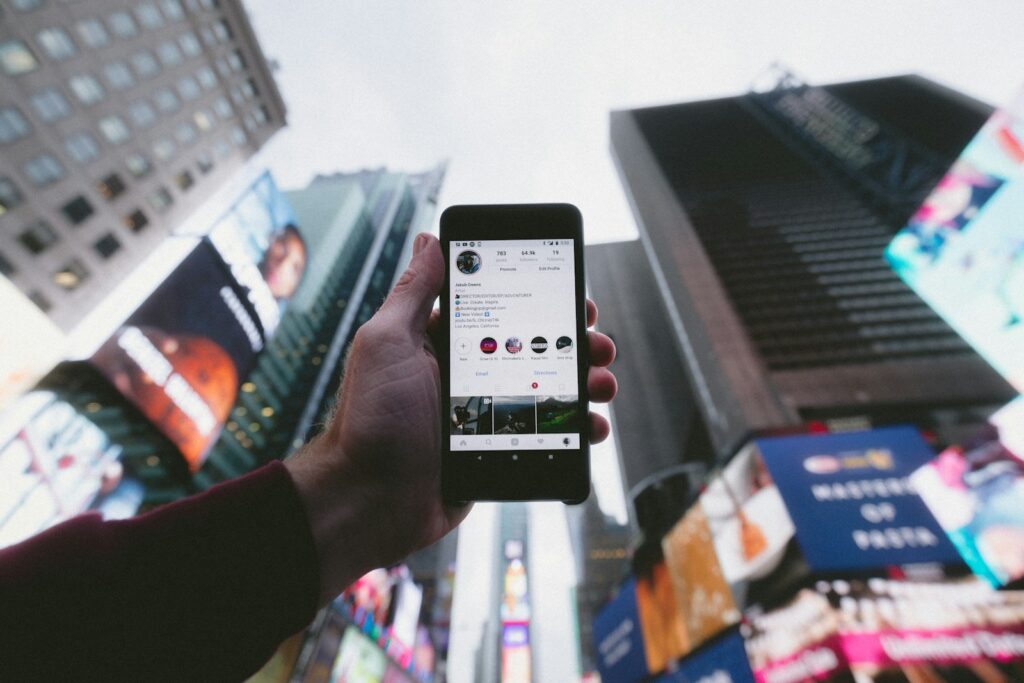 Navigating Social Media Law in 2025 2 high angle photo of person holding turned on smartphone with tall buildings background