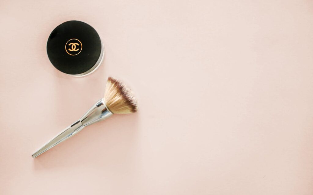 Branding Strategies: How to Build a Memorable and Profitable Brand 4 Sophisticated flatlay of a makeup brush and branded cosmetic jar on a pastel background.